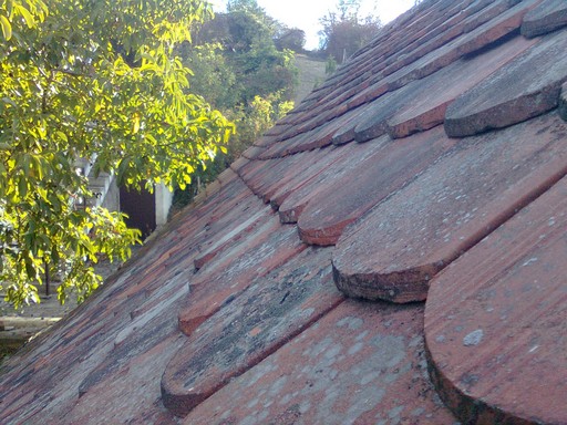 Roof tile at the far end of the photo is starting to show a slight bowing inward toward the house interior. 