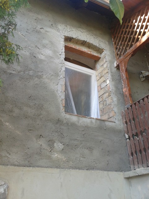 The old window was removed, and a new brick frame was built to fit the new window. The first undercoat plaster layer has also been applied to the wall.