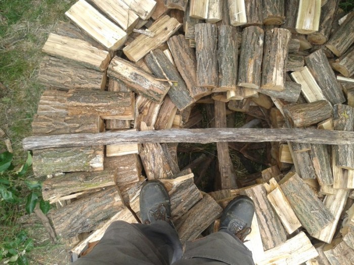 Empty center hole showing placement of horizontal wood poles added at 90 degree angles as the pile is built to increase stability. I am standing on the pile to take this picture, showing how stable this wood pile is.