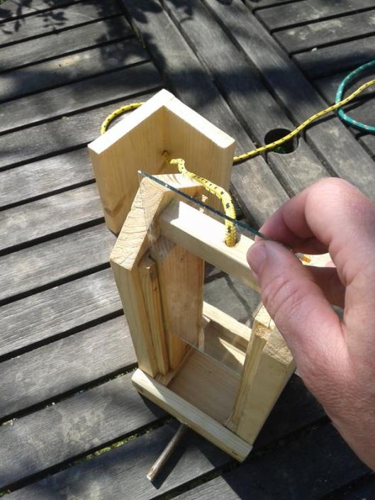 Inserting cut glass into bird feeder.